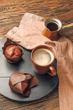 Ot, bir fincan taze kahve ve ahşap masada çörekler.