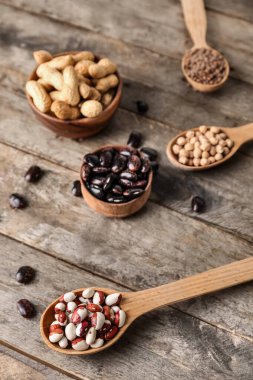 Tahta arka planda farklı baklagiller ve kaşıklar