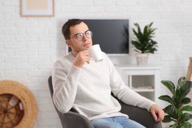 Genç adam evde çay içiyor.