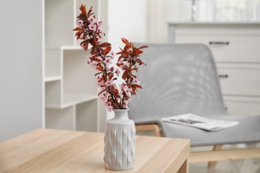 Odada çiçek açan güzel dalları olan bir vazo.