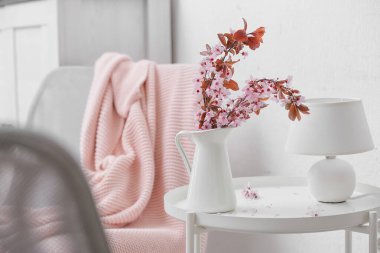 Odada çiçek açan dalları olan bir sürahi.