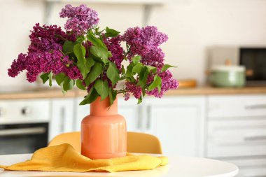 Mutfaktaki masada leylak çiçekli vazo.