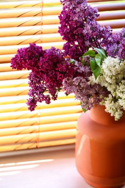 Pencere kenarında leylak çiçekli vazo