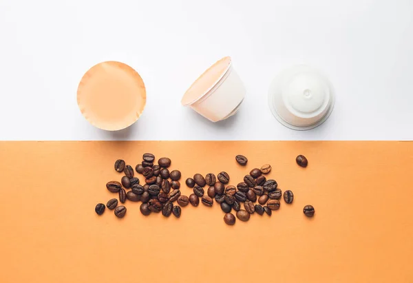 Coffee capsules with beans on color background