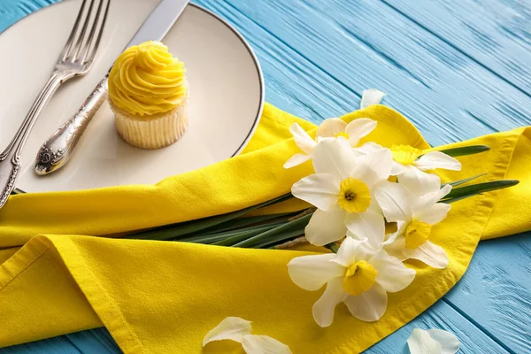 Schöne Tischdekoration Mit Narzissenblumen Und Cupcake Auf Farbigem Holzhintergrund Nahaufnahme — Stockfoto