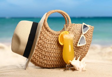 Plaj aksesuarları, tropikal bir tatil köyünde kumların üzerinde bir bardak kokteyl.