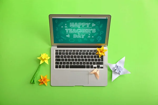 Text HAPPY TEACHER\'S DAY on screen of laptop and paper narcissus on color background