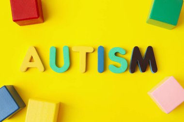 Renk arkaplanındaki sözcük AUTISM ve küpleri