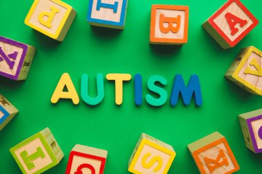 Renk arkaplanındaki sözcük AUTISM ve küpleri
