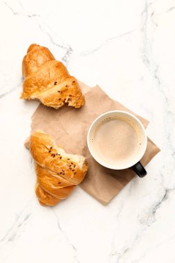 Bir fincan taze kahve ve mermer arka planda kruvasan.