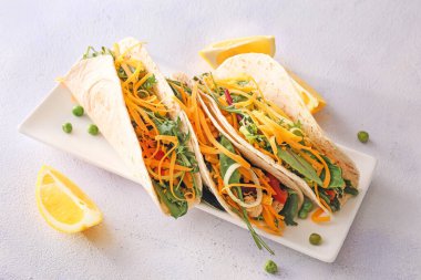 Hafif arka planda lezzetli taco ve limon tabağı.