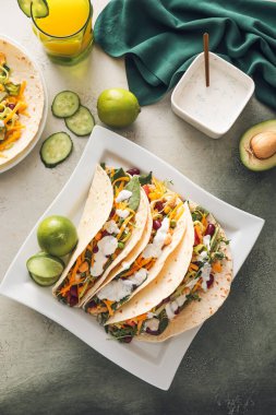 Lezzetli taco, sos ve bir bardak meyve suyu ile renklendirilmiş tabak.