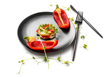 Beyaz arka planda lezzetli makarna, dolmalık biber ve mikroyeşil tabaklar.