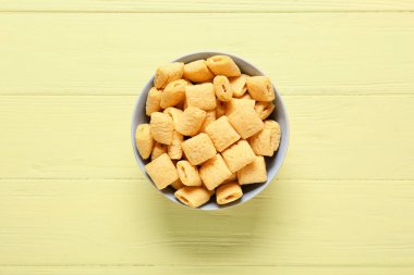 Renkli ahşap arka planda lezzetli mısır yastıkları olan bir kase.