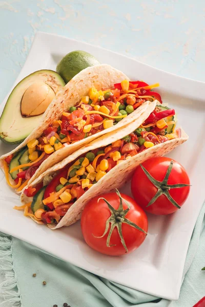 Plate with tasty tacos and vegetables on color background