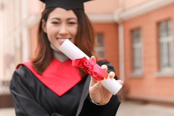 在毕业典礼上身穿学士袍并取得毕业证书的女学生 — 图库照片