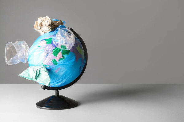 Творческая композиция с глобусом и мусором на сером фоне. Концепция экологии