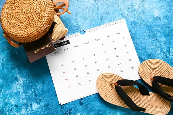 Calendar, passport and beach accessories on color background