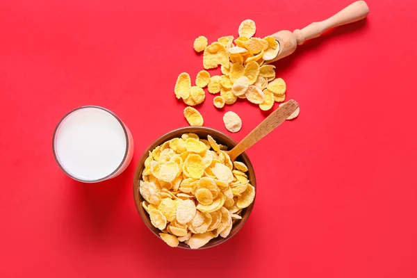 Glass of milk and tasty corn flakes on color background