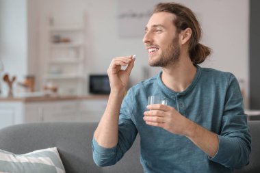 Yakışıklı genç adam evde hap alıyor.