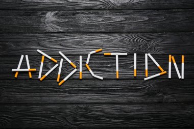 Sözcük Bağımlılığı: Ahşap arka planda sigaradan yapılmış