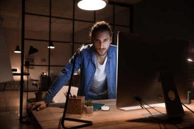 Geceleri ofiste çalışan yakışıklı adam.