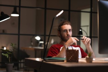 Geceleri ofiste çalışan yakışıklı adam.