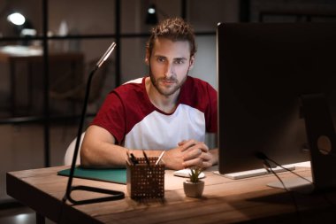 Geceleri ofiste çalışan yakışıklı adam.