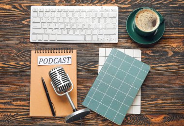 Retro mikrofon, bilgisayar klavyesi, PODCAST yazılı kağıt ve tahta arka planda bir fincan kahve.