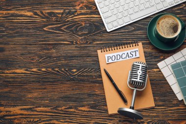 Retro mikrofon, bilgisayar klavyesi, PODCAST yazılı kağıt ve tahta arka planda bir fincan kahve.