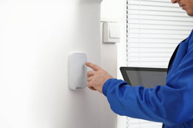 Tablet bilgisayarı olan işçi alarm sistemini içeride kontrol ediyor