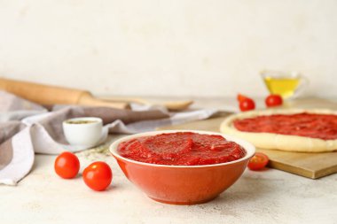 Açık arkaplanda lezzetli domates soslu pizza hamuru, yakın plan.