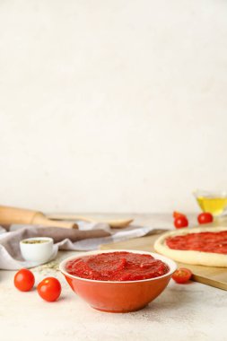 Açık arkaplanda domates soslu pizza hamuru.