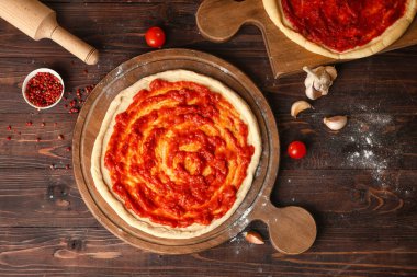 Tahta arka planda lezzetli domates soslu pizza hamuru.
