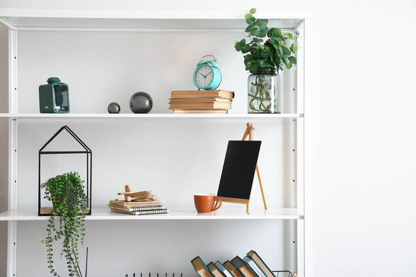 Modern book shelf with decor near light wall