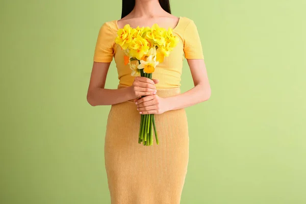 Beautiful young woman with  narcissus bouquet on color background