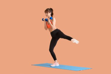 Renkli arka planda dambıllarla spor yapan genç bir bayan.