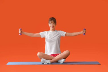 Renkli arka planda dambıllarla spor yapan genç bir bayan.