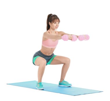 Beyaz arka planda dambıllarla spor yapan genç bir bayan.