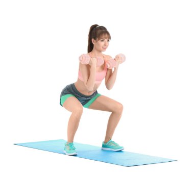 Beyaz arka planda dambıllarla spor yapan genç bir bayan.