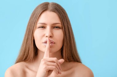 Yaratıcı makyajlı güzel bir genç kadın, arka planda sessizlik jesti yapıyor.