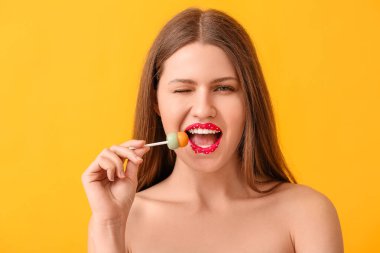 Yaratıcı makyajlı güzel genç bir kadın ve renkli arka planda tatlı bir lolipop.