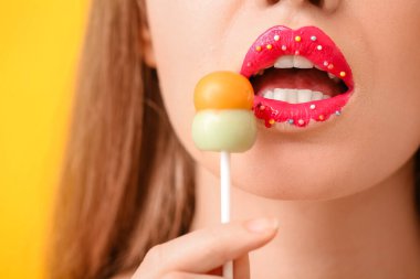 Yaratıcı makyajı ve tatlı lolipopu olan genç ve güzel bir kadın.
