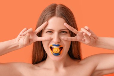 Yaratıcı makyajlı ve kimyonlu güzel genç bir kadın renk geçmişinde zafer jesti sergiliyor.