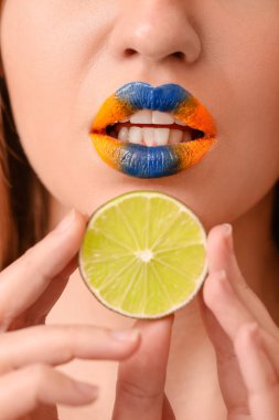 Yaratıcı makyajı ve limonu olan güzel genç bir kadın. Yakın plan.