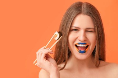 Yaratıcı makyajlı ve arkaplanda lezzetli suşi yuvarlanan güzel genç bir kadın.