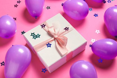 Hava balonları, hediye kutusu ve renkli arka planda konfeti.