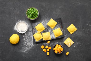 Koyu arkaplanda çiğ ravioli olan ahşap tahta.