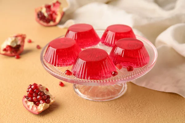 Dessert stand with tasty pomegranate jelly on color background