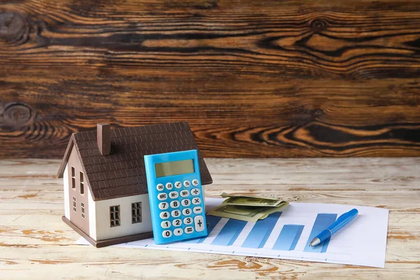 带有房屋模型 图表和木制背景货币的计算器 — 图库照片